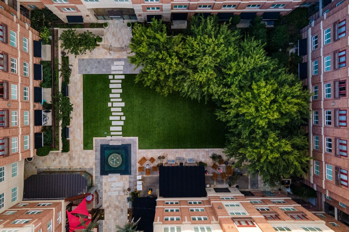 Hanover Company Aerial view of a rectangular courtyard with green lawn, fountain, stone path, and surrounding red-brick buildings.