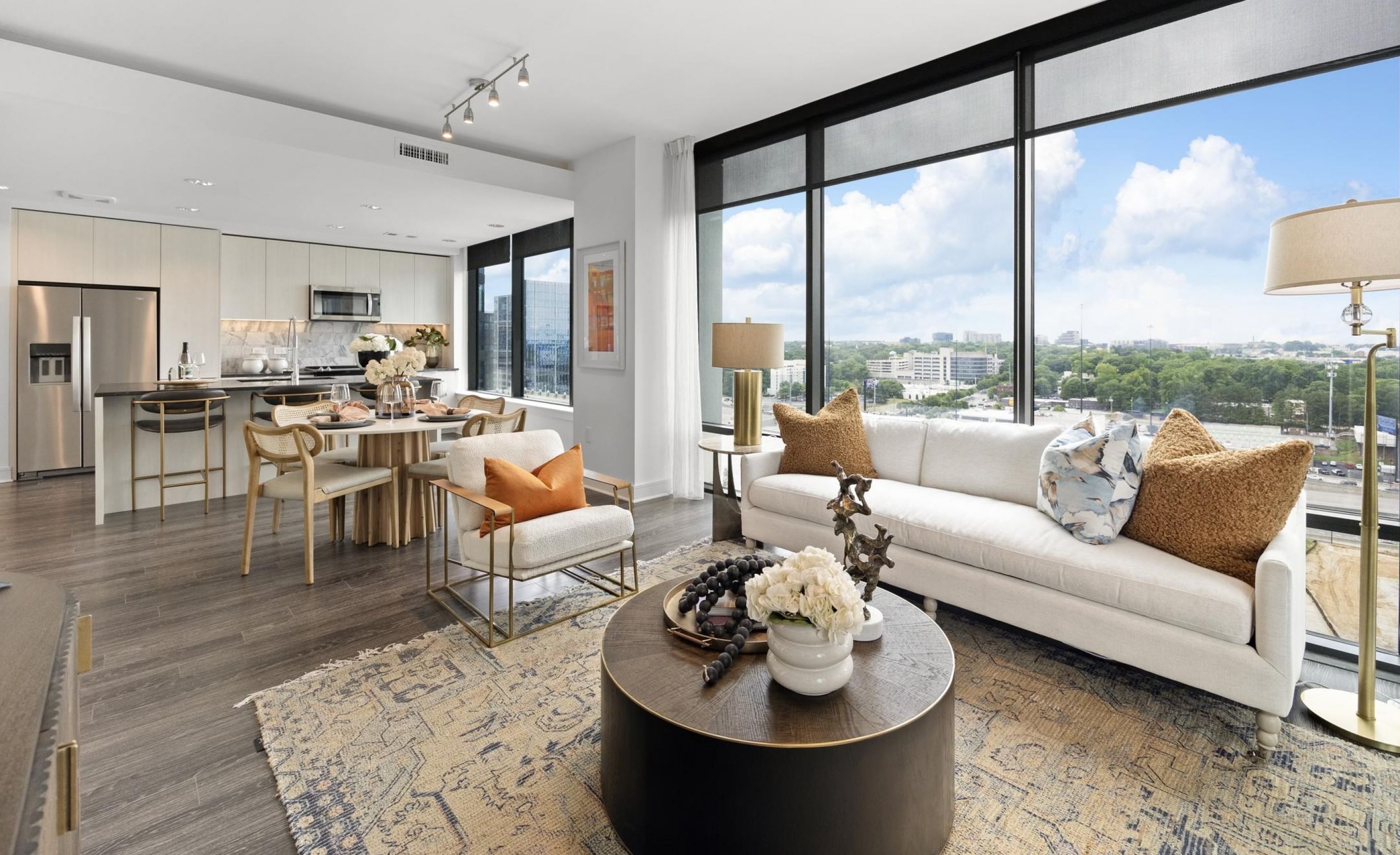 Modern open-concept living room and kitchen with large windows, city view, and stylish decor at Hanover Corporate's Hanover Midtown apartments.