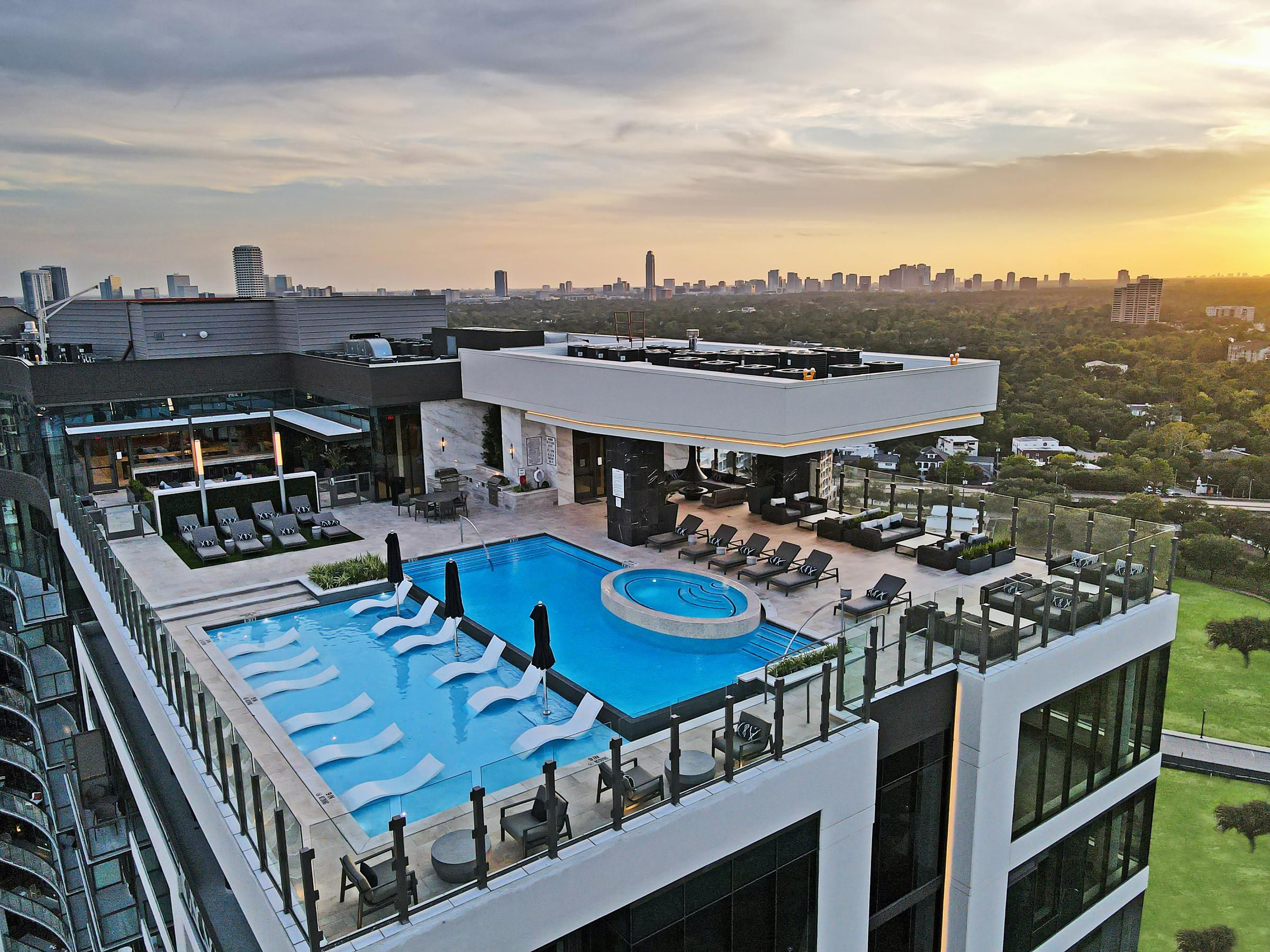Rooftop pool with lounge chairs and a view of the city skyline at sunset at a Hanover Company property.