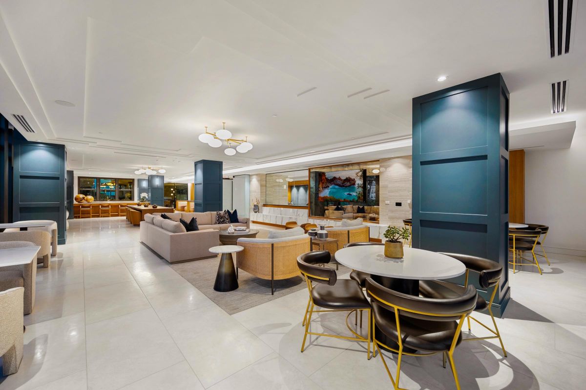 Spacious modern lounge with sofas, tables, and art. Bright lighting and elegant decor with a neutral color palette.