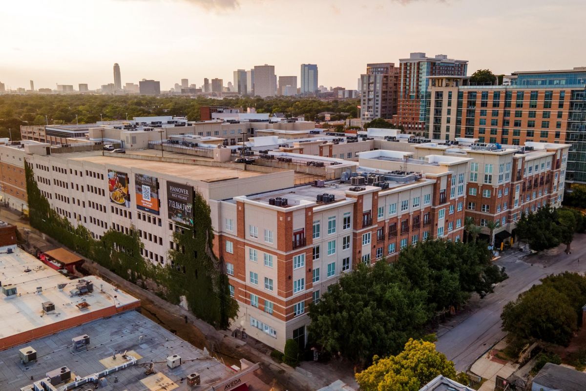 Hanover Company Aerial view of cityscape with residential buildings and skyline in the background at sunset.
