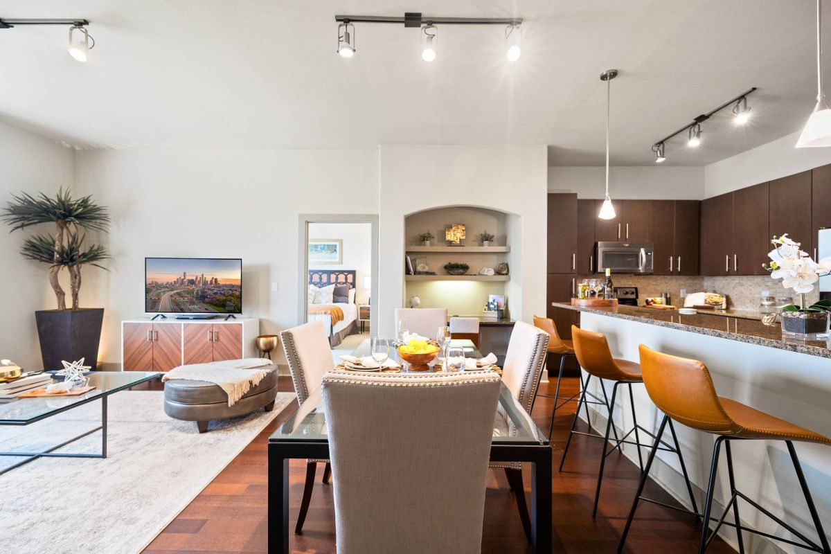 Hanover Company, Hanover Rice Village Modern open-plan living and dining area with a kitchen, featuring sleek furniture, ambient lighting, and contemporary decor.