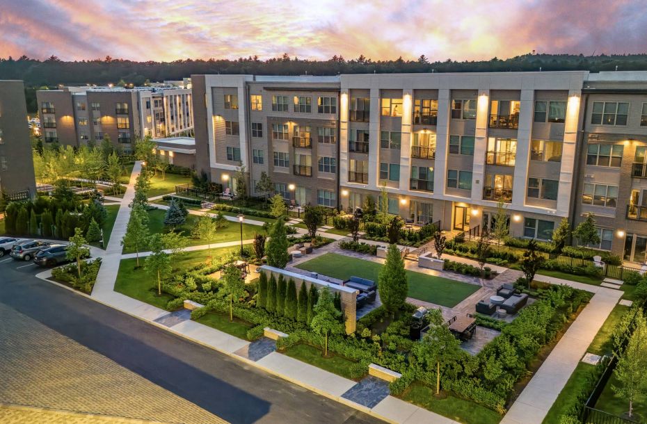 Hanover Company, Hanover Colony Place Aerial view of modern apartment buildings surrounded by greenery at sunset.