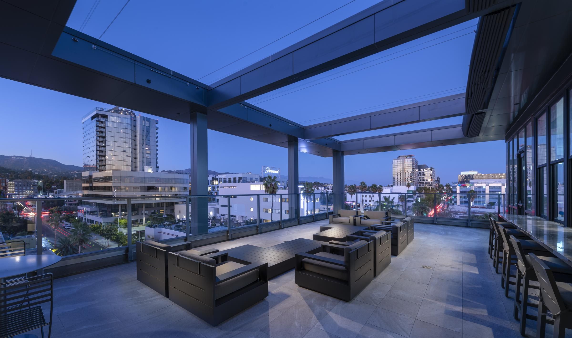Rooftop lounge at dusk with modern seating, overlooking city skyline and illuminated buildings at Hanover Hollywood.