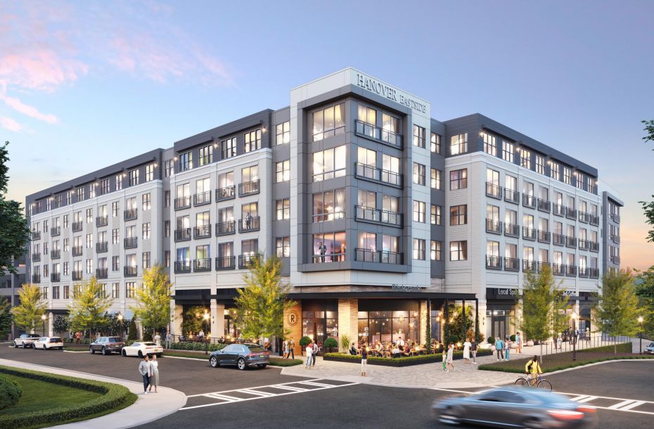 Modern multi-story building with large windows, ground-floor businesses, and pedestrians on surrounding sidewalks.