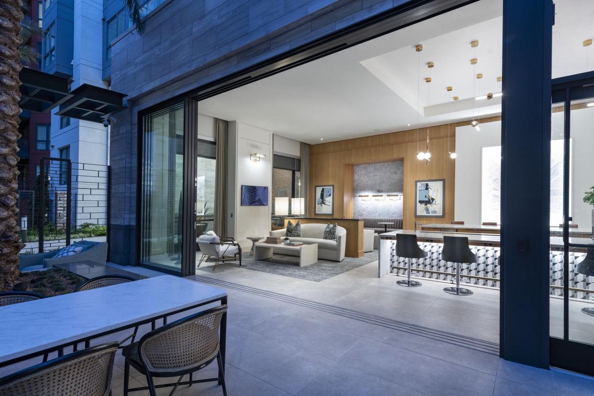 Modern indoor-outdoor living space with an open sliding door, stylish seating, and contemporary lighting.