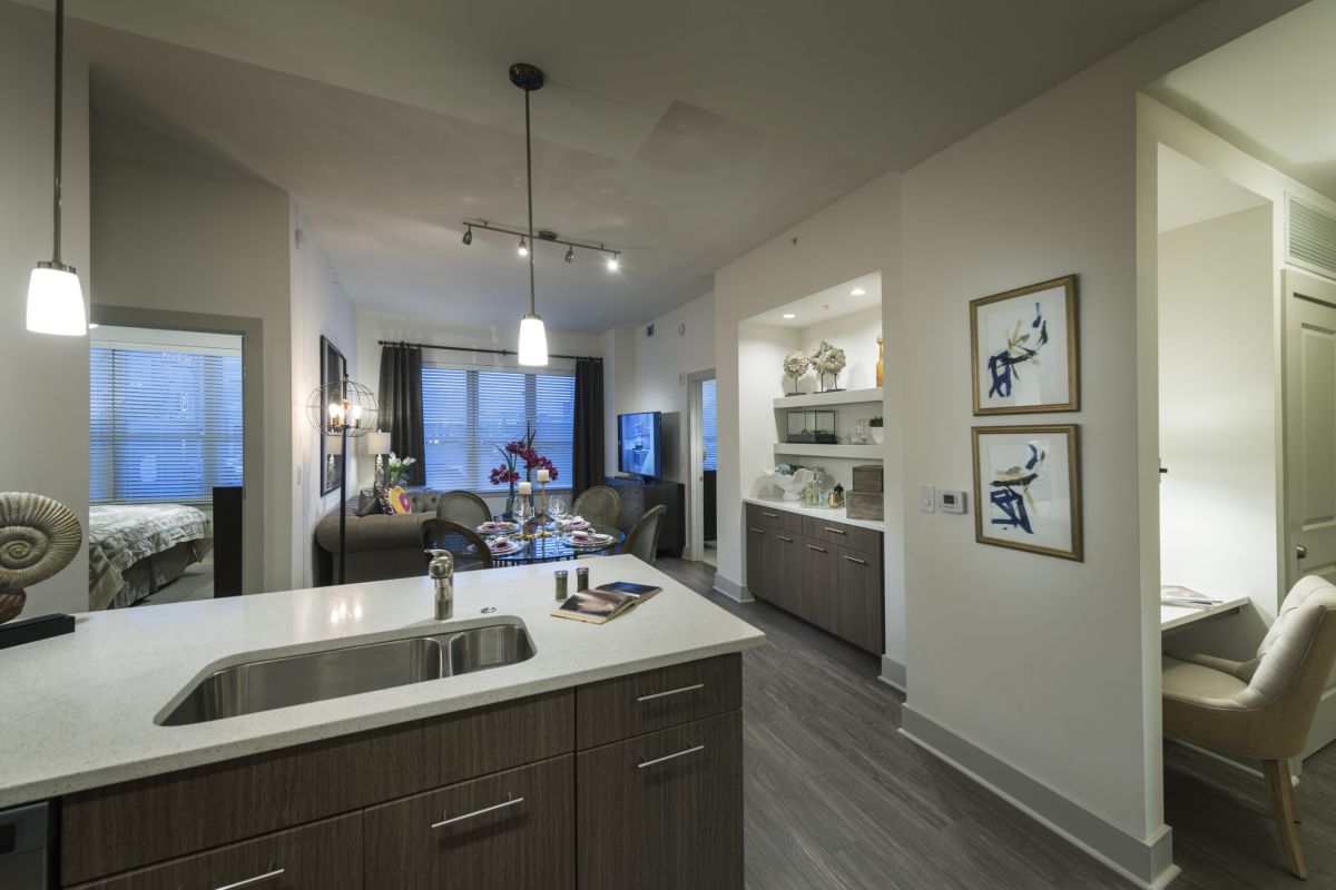 Modern open-concept apartment with kitchen island, dining area, living room, and small office nook.