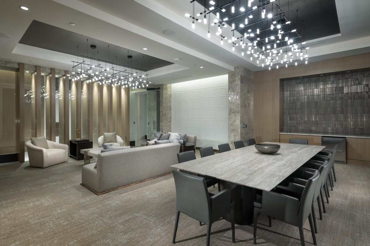 Modern lounge with a large dining table, plush seating, and contemporary lighting fixtures.