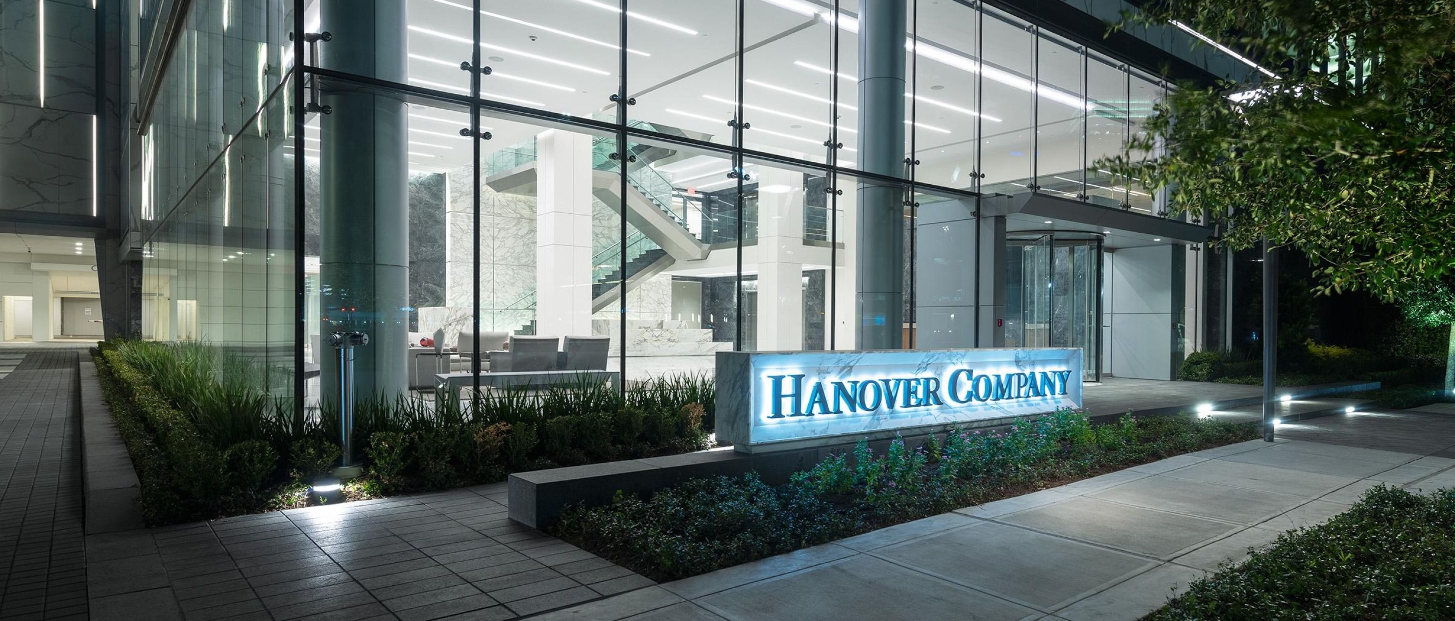 Glass-fronted office building at night with "Hanover Company" sign illuminated.