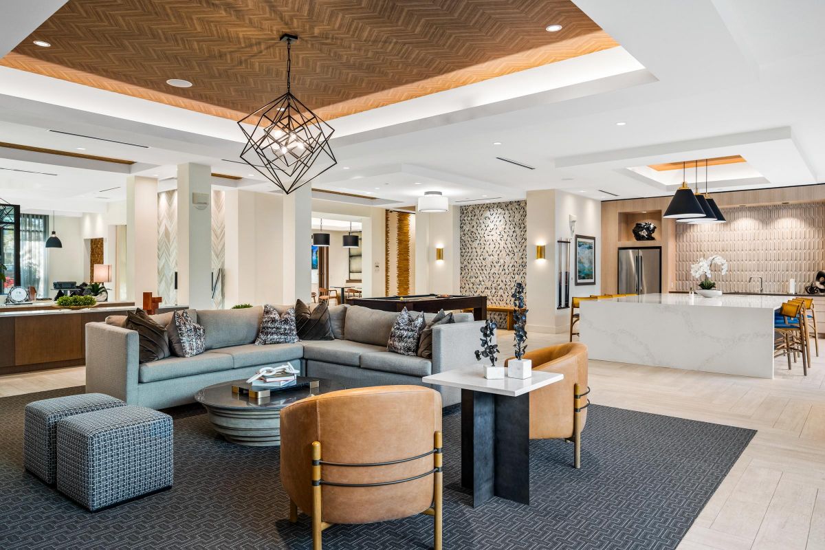 Luxurious modern living room with a sectional sofa, geometric lighting, and kitchen area visible in the background.