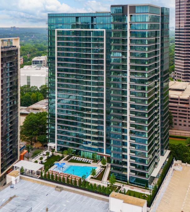 Hanover Company Aerial view of modern skyscrapers with glass facades, a rooftop pool, and surrounding cityscape under a blue sky.