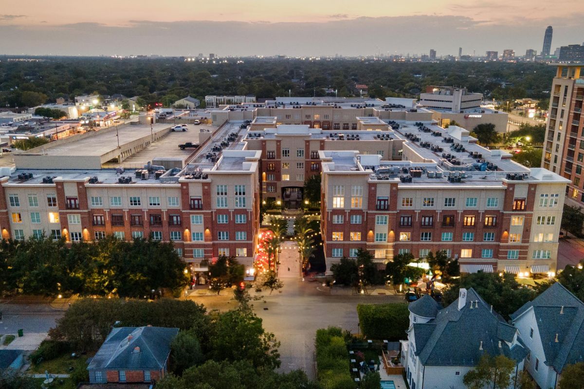 Hanover Company Aerial view of a cityscape at dusk with buildings, roads, and trees illuminated under a pastel sky.
