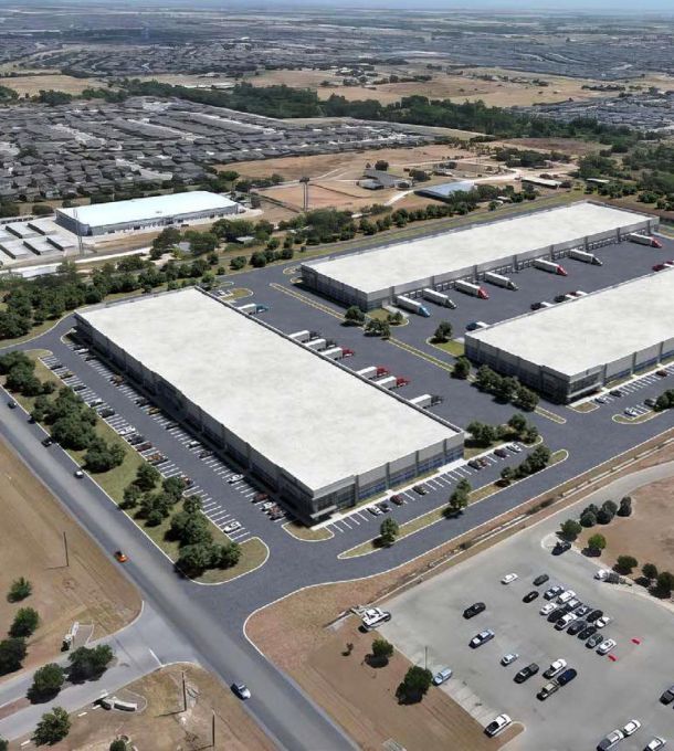Hanover Company Aerial view of a large industrial complex with three rectangular warehouse buildings and numerous parked trucks.