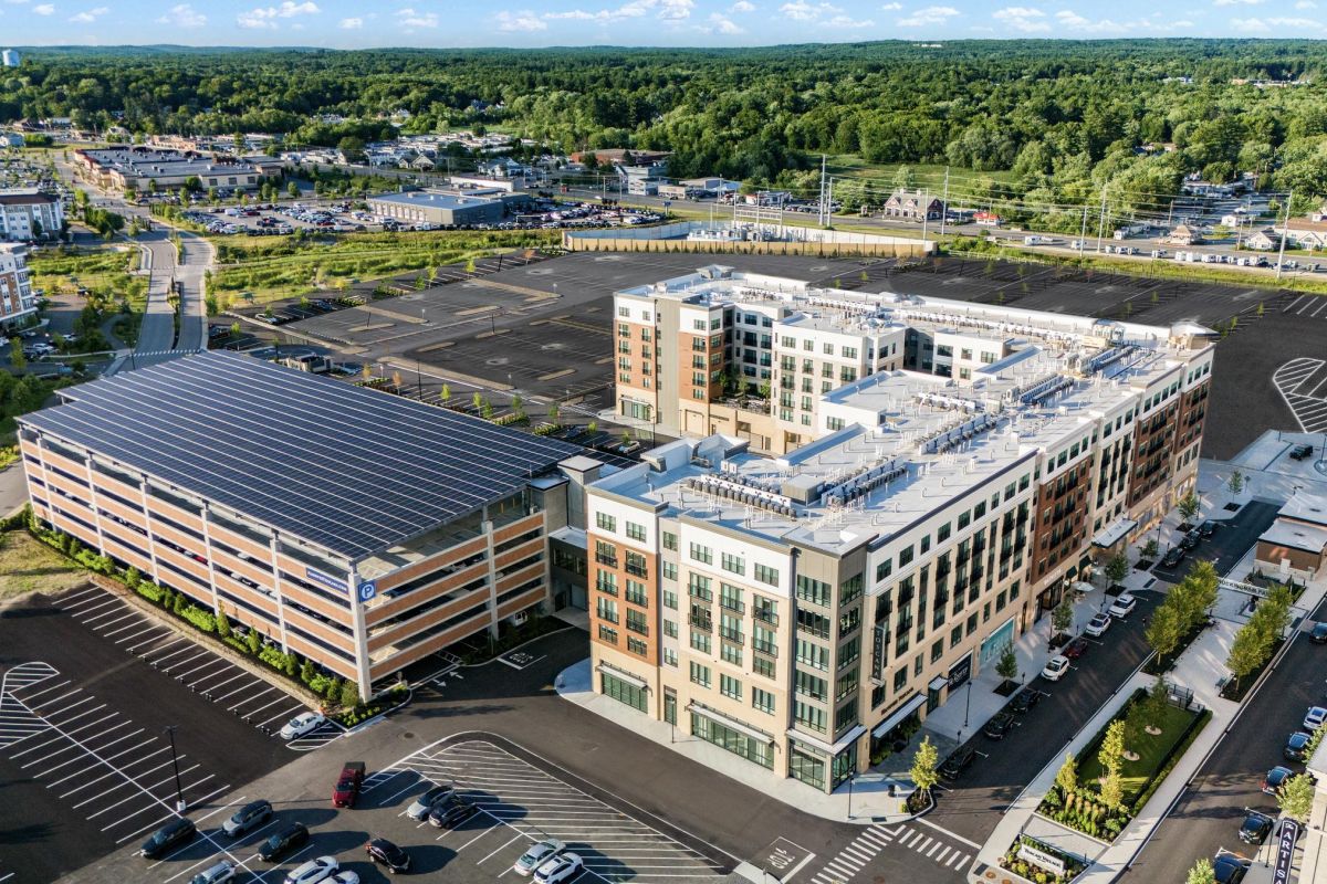 Aerial view of a modern office complex with a solar-paneled parking deck and surrounding greenery.