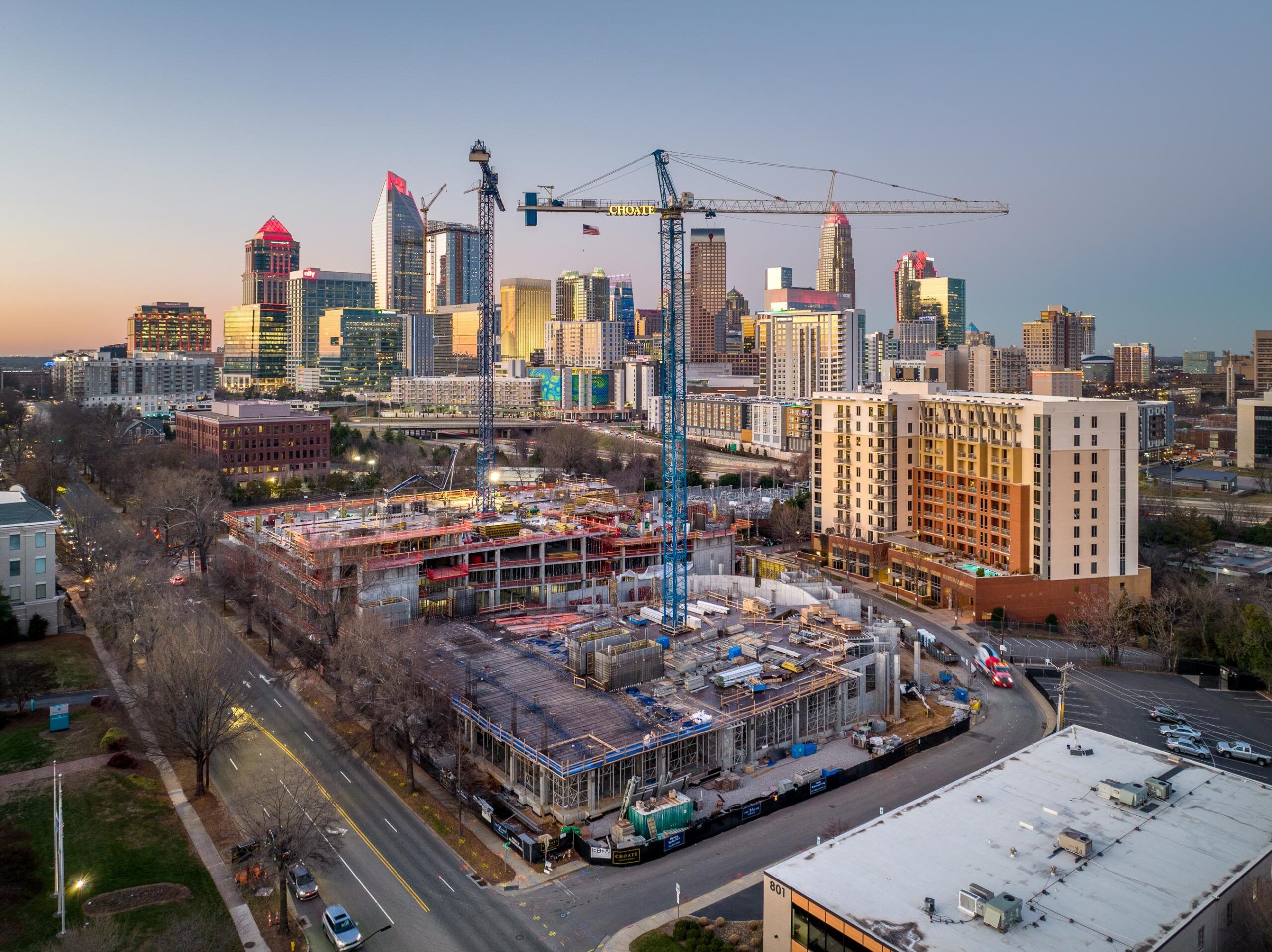 Aerial view of a city skyline at sunset with cranes and buildings under construction in the foreground for a Hanover Company property.
