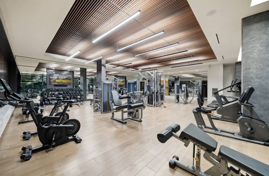 Hanover Company, Hanover RiNo Modern gym with exercise machines, weights, and wood ceiling. Bright lighting and spacious layout.