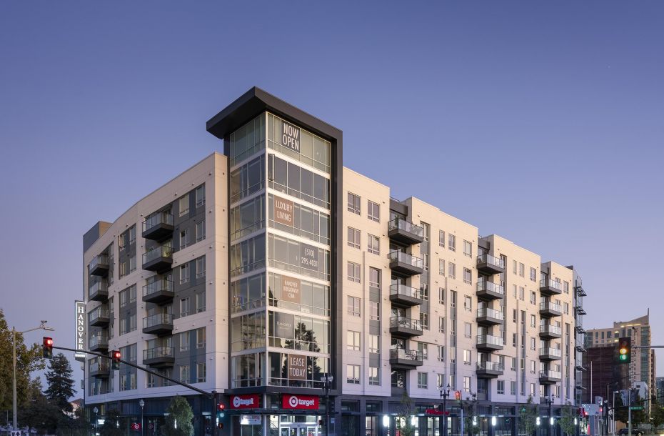 Modern multi-story apartment building with retail stores, including Target, on the ground floor at dusk.