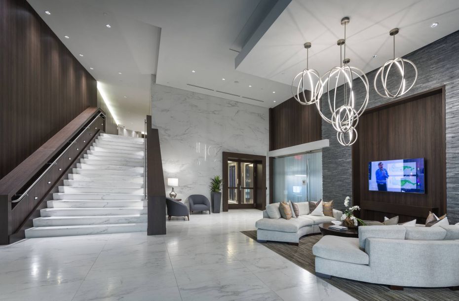Hanover Company, Hanover Buckhead Village Modern hotel lobby with marble stairs, elegant seating, and a contemporary chandelier.