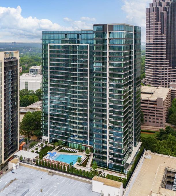 Hanover Company Aerial view of modern skyscrapers with glass facades, a rooftop pool, and surrounding cityscape under a blue sky.