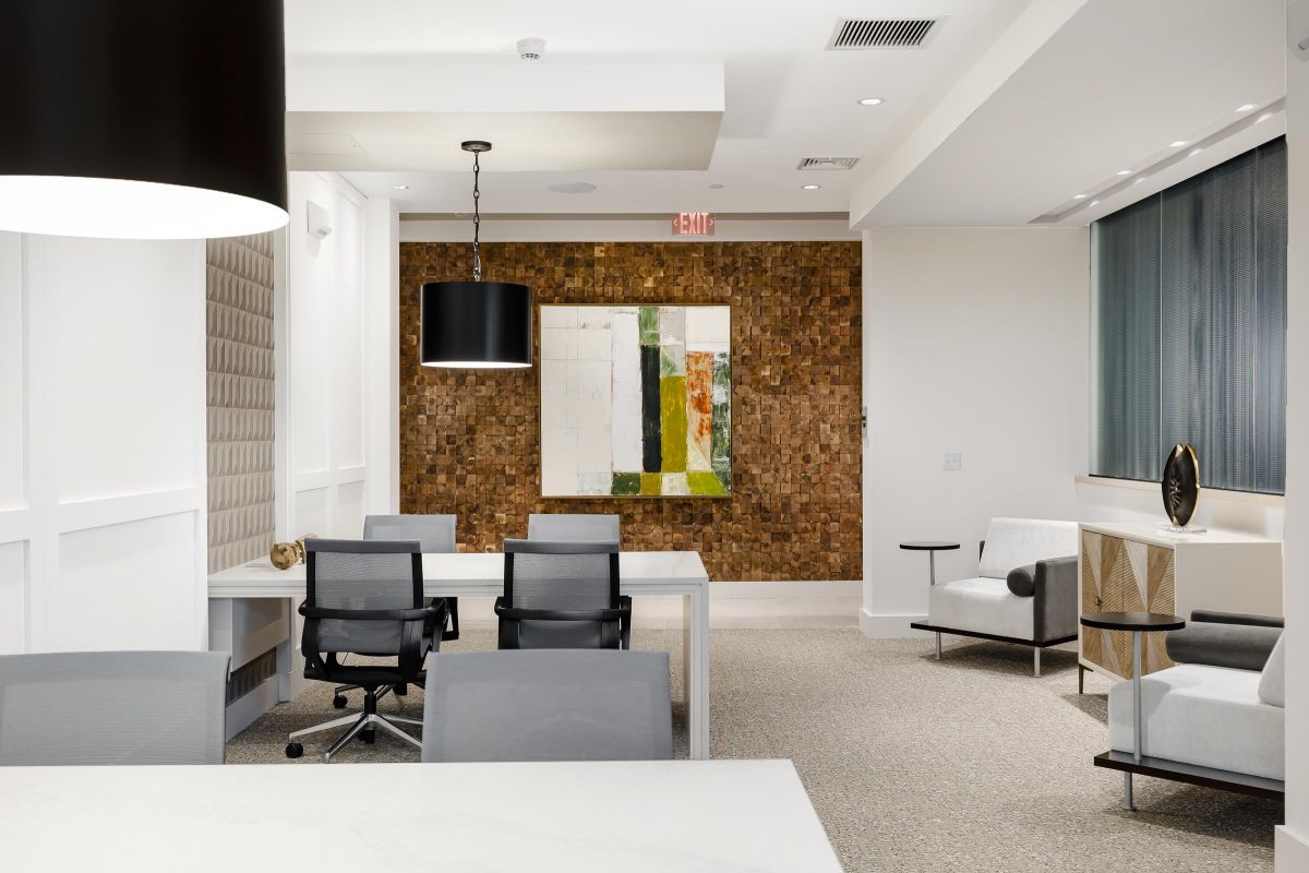 Modern office space with chairs, tables, abstract wall art, and a textured wall design.