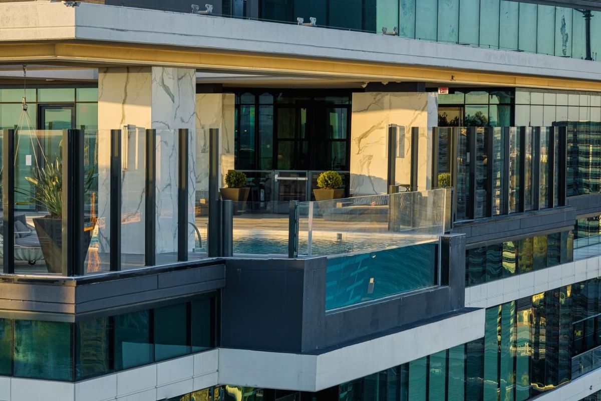 Rooftop terrace with glass railings on a modern high-rise building, overlooking a cityscape.