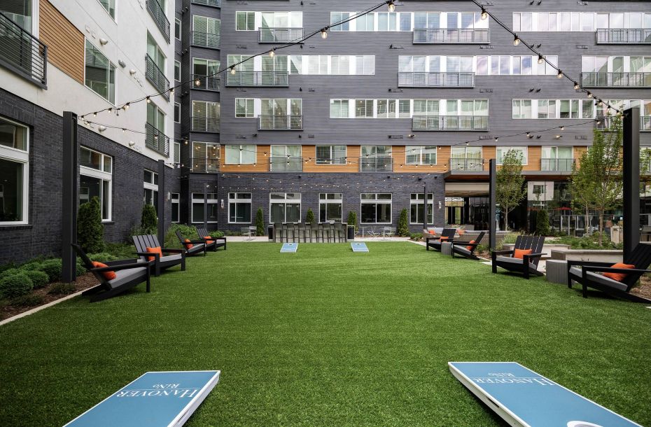 Hanover Company, Hanover RiNo Modern apartment courtyard with grass, string lights, loungers, and cornhole boards.