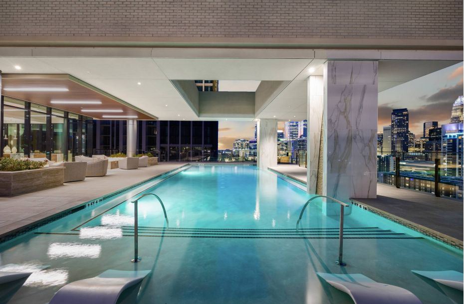 Hanover Company, The Driscoll at River Oaks Luxurious rooftop pool area with city skyline views, featuring poolside lounge chairs and large windows.