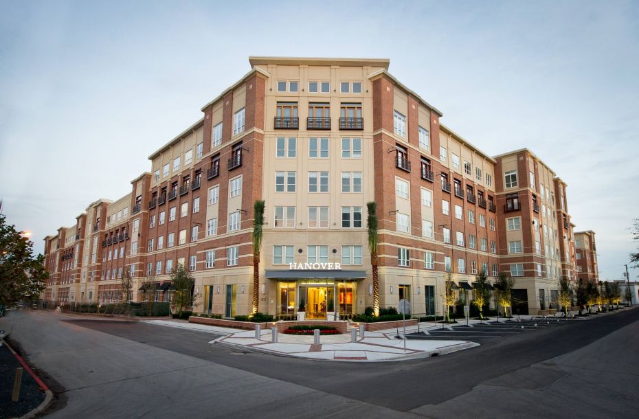 Hanover Company, Hanover Rice Village Large multi-story brick apartment building with "Hanover" sign above entrance, surrounded by roads and sidewalks.
