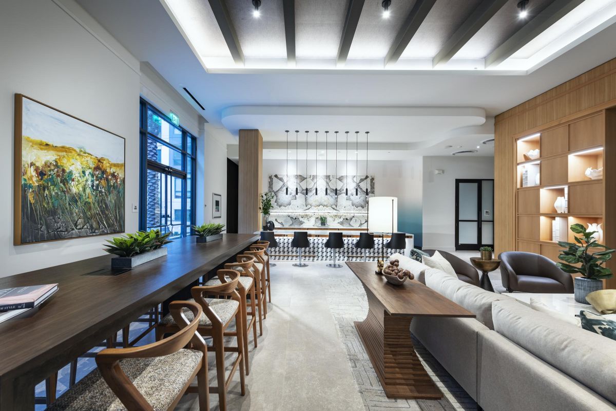 Modern open-concept living space with a long wooden dining table, sofas, and elegant lighting.