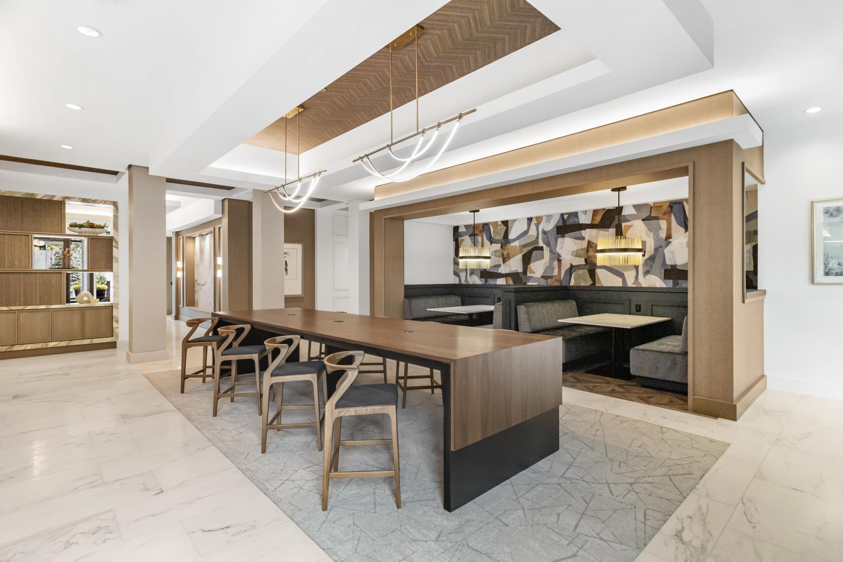 Spacious modern dining area with long wooden tables, brown chairs, and large windows offering a scenic view.