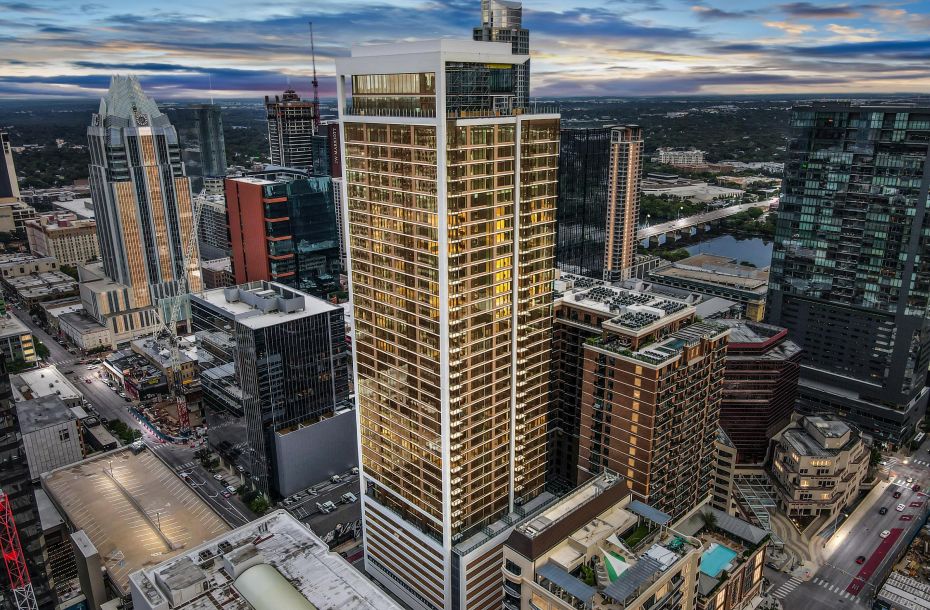 Aerial view of a city skyline at dusk with tall skyscrapers and a colorful sky.