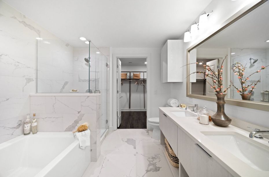 Hanover Company, Hanover Midtown Modern bathroom with marble tiles, shower, bathtub, double sinks, and decorative branches on the counter.